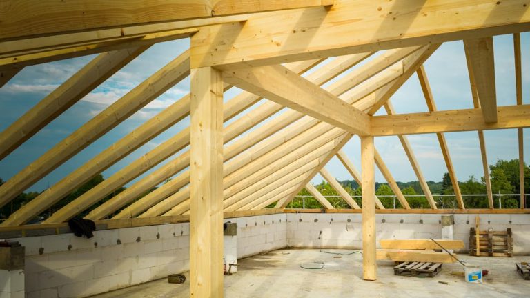 Unfinished construction site with a focus on wooden roof trusses under a clear sky.