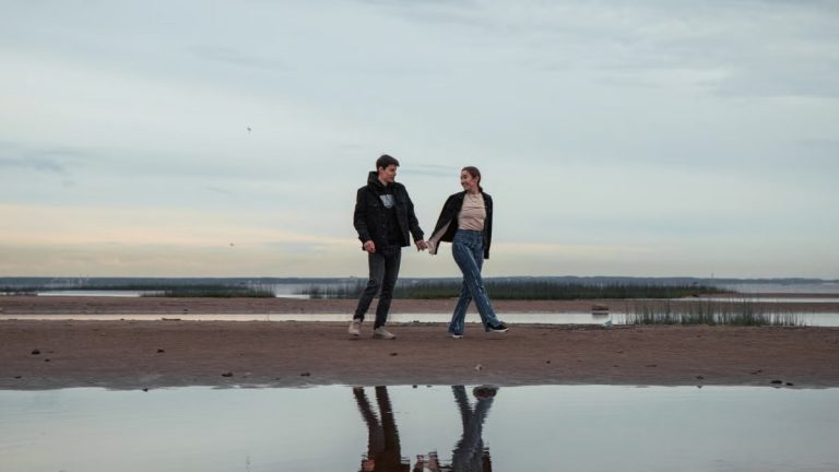A couple holding hands and walking on a tranquil beach at dawn reflecting their love and connection.