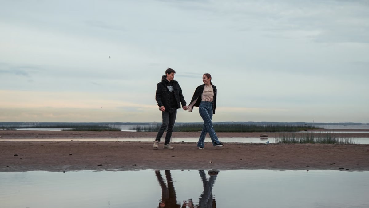 A couple holding hands and walking on a tranquil beach at dawn reflecting their love and connection.